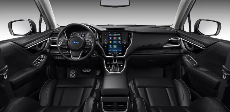 Parte interna delantera de Subaru Outback, con vista a volante, tablero, control de cambios, pantalla inteligente y asientos de piloto y copiloto. 