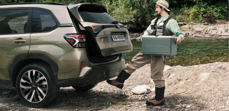 SUV Subaru Forester estacionado en frente de lago con persona detrás.  